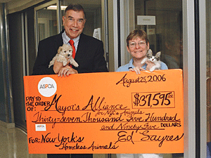 ASPCA President Edwin Sayres (assisted by two furry friends) presents a check to Mayor's Alliance President Jane Hoffman. The ASPCA and the big-hearted New Yorkers who answered its challenge are helping to keep the wheels turning on the Mayor's Alliance transport van.